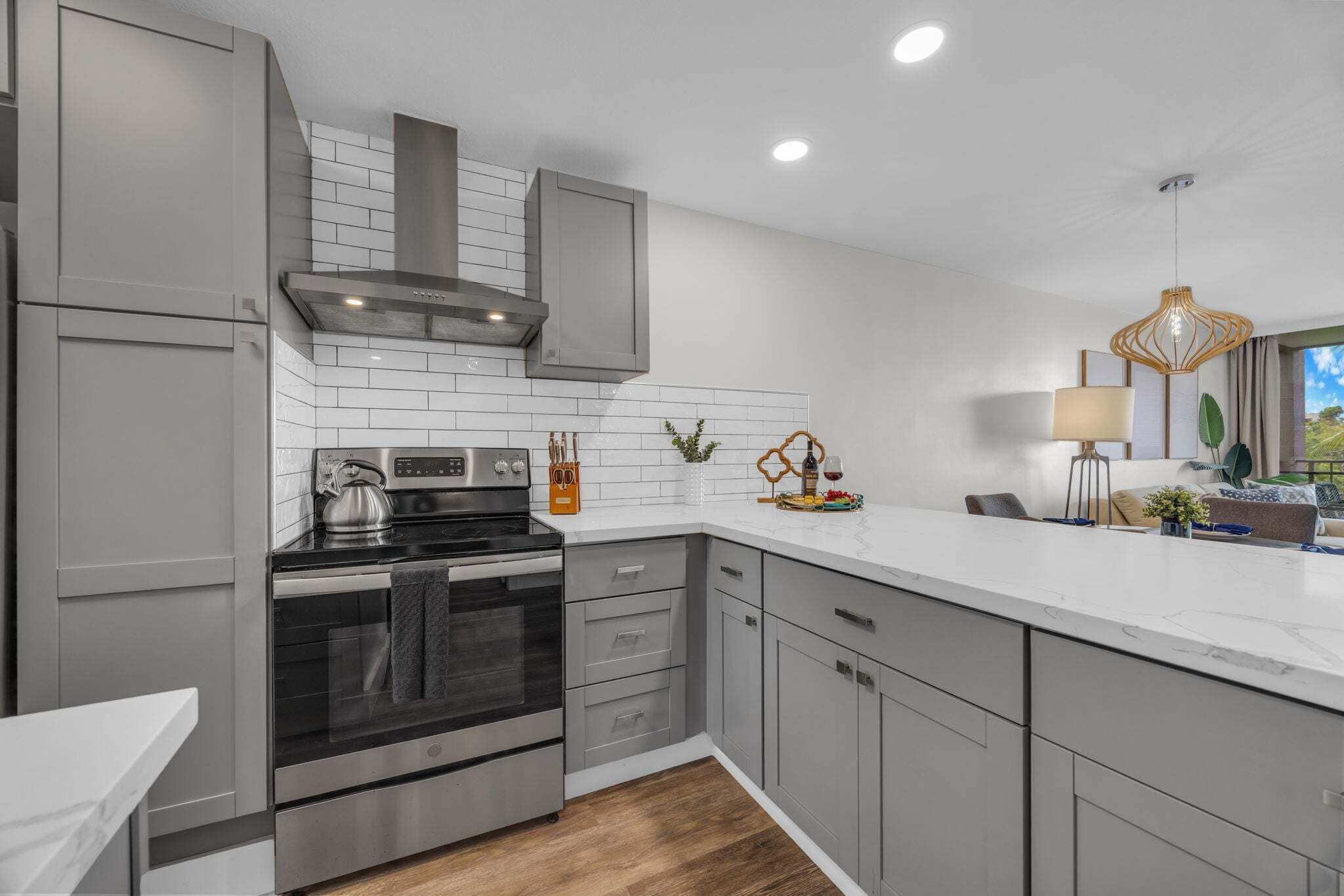 A modern kitchen with grey cabinetry, a stainless steel stove, and a white countertop.