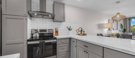 A modern kitchen with grey cabinetry, a stainless steel stove, and a white countertop.