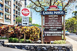 A street sign with a list of shops including a pub, cafe, and various retail stores. - Chic, Upgraded 2BR with Stunning Ocean Views (Lahaina)