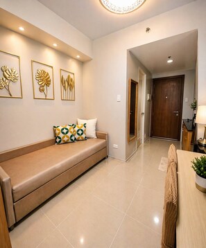 A modern living room with a sofa, a coffee table, and a dining area. - Vibrant Studio Apartment in Vibrant Pasay, Philippines (Pasay)