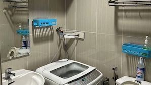 Un baño pequeño con lavamanos, inodoro y lavadora.