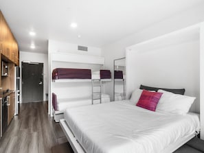 A modern hotel room with bunk beds, a kitchenette, and a large bed with pillows. - Canyon Haus 326 | Modern Studio | Mountain View | Heated Pool | Hot Tub | WiFi (Park City)