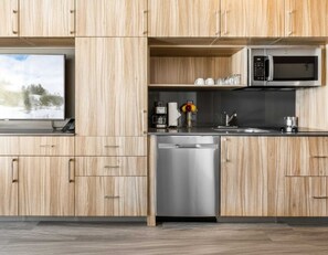 Eine moderne Küche mit Holzschränken, einem Geschirrspüler, einer Kaffeemaschine und einer Mikrowelle.