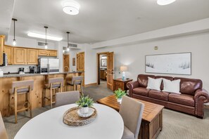 A modern kitchen with wooden cabinets, a dining area with a round table, and a brown leather sofa. - Silverado 126 | Mountain View | Patio | Pool | Short Walk to Lift (Park City)