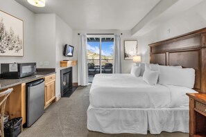 Ein Hotelzimmer mit Bett, Schreibtisch mit Mikrowelle, Kamin und Balkon mit Blick.