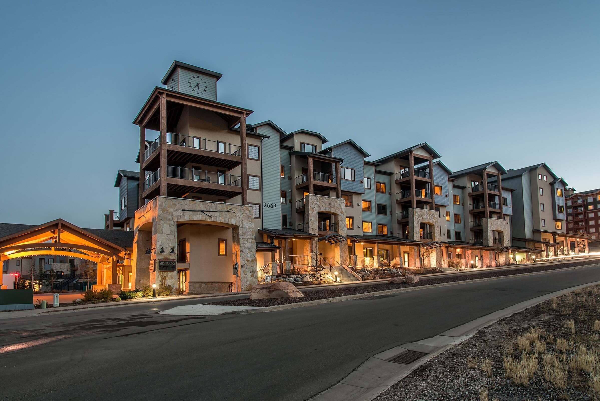 A multi-story hotel with balconies, a stone facade, and a well-lit entrance.