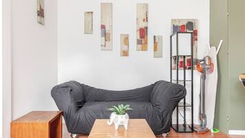 A living room with a black sofa, a wooden coffee table, and a white decorative pot.