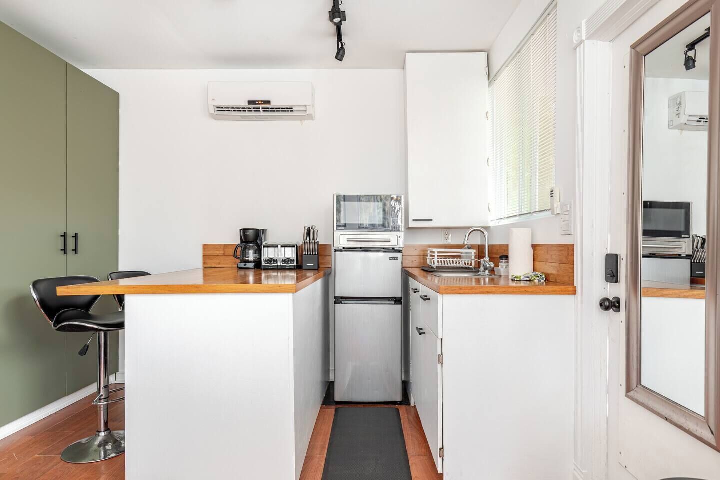 A compact kitchen with a refrigerator, microwave, toaster, and coffee maker.