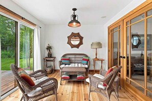 A cozy room with wicker furniture, a large window, and a wooden cabinet. - Peaceful Elkhorn Aspen Retreat with Amenity Access (Sun Valley)