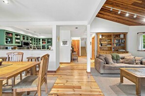 A spacious living area with a wooden floor, a dining table with chairs, a sofa, and a bookshelf. - Peaceful Elkhorn Aspen Retreat with Amenity Access (Sun Valley)