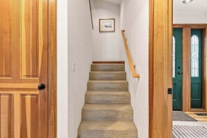 A wooden staircase with a textured carpet leading to a door with a green frame and glass panels. - Peaceful Elkhorn Aspen Retreat with Amenity Access (Sun Valley)