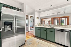 A modern kitchen with stainless steel appliances, a built-in dishwasher, and a large window providing natural light. - Peaceful Elkhorn Aspen Retreat with Amenity Access (Sun Valley)