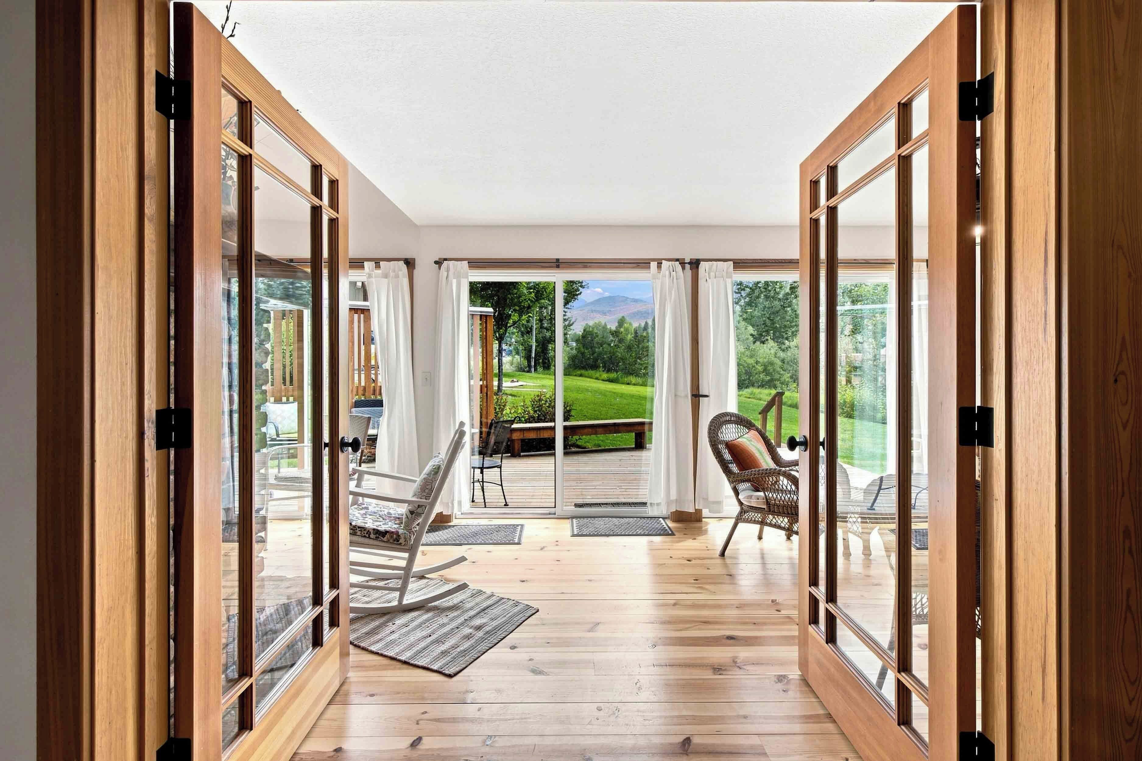 A room with a wooden floor, a sliding glass door leading to an outdoor deck with a view of a green landscape.