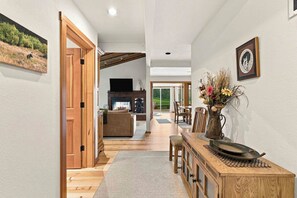 A spacious hallway with wooden flooring, a dining area with a table and chairs, and a fireplace. - Peaceful Elkhorn Aspen Retreat with Amenity Access (Sun Valley)