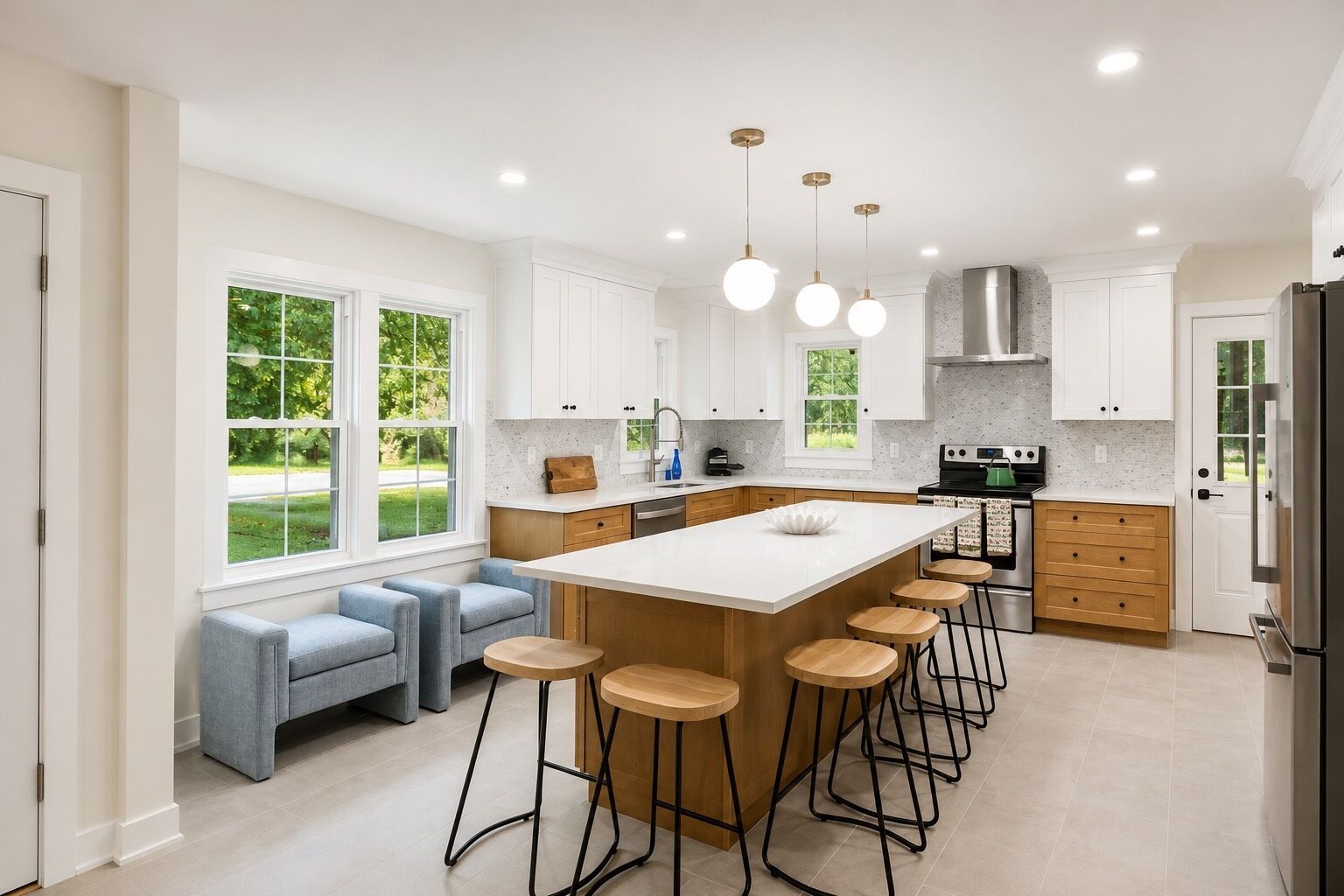 Een moderne keuken met een groot eiland, barkrukken en een zithoek met een bank.