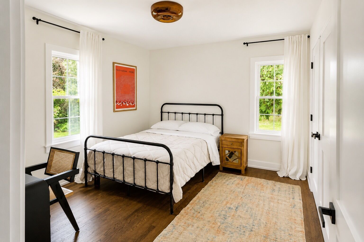 A bedroom with a bed, a nightstand, a chair, and a window.