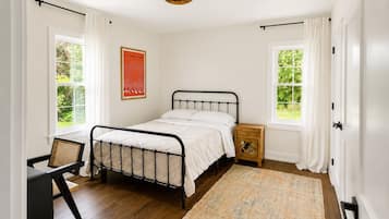 A bedroom with a bed, a nightstand, a chair, and a window.
