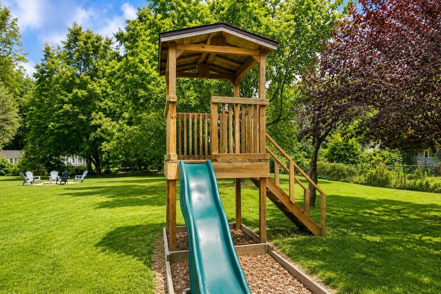 A wooden play structure with a slide in a grassy park area.