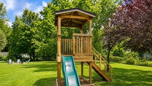 A wooden play structure with a slide in a grassy park area. - Home in Union Pier, MI (Union Pier)