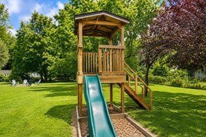 Eine Holzspielkonstruktion mit Rutsche in einem grünen Park.