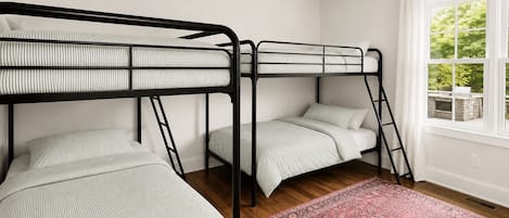 Una habitación con literas, una ventana con vista a zonas verdes y una alfombra estampada.