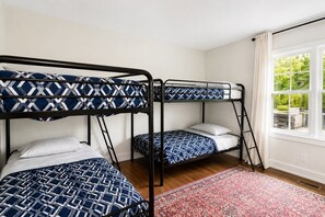 Ein Zimmer mit Stockbetten, einem fensterbelaubten Fenster und einem gemusterten Teppich.