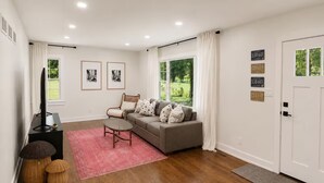 A modern living room with a sofa, a coffee table, a TV, and a door with license plates. - Home in Union Pier, MI (Union Pier)