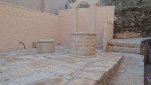 A stone courtyard with a central pillar, a small round stone, and a low wall. - Casa Lago-Marí — Large house near the sea (Lariño)