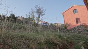 Ländliche Landschaft mit einer Steinmauer, einem blauen Haus und einem roten Gebäude.