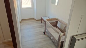 Une pièce avec un plancher en bois, une petite table et un lit doté d’une tête de lit.
