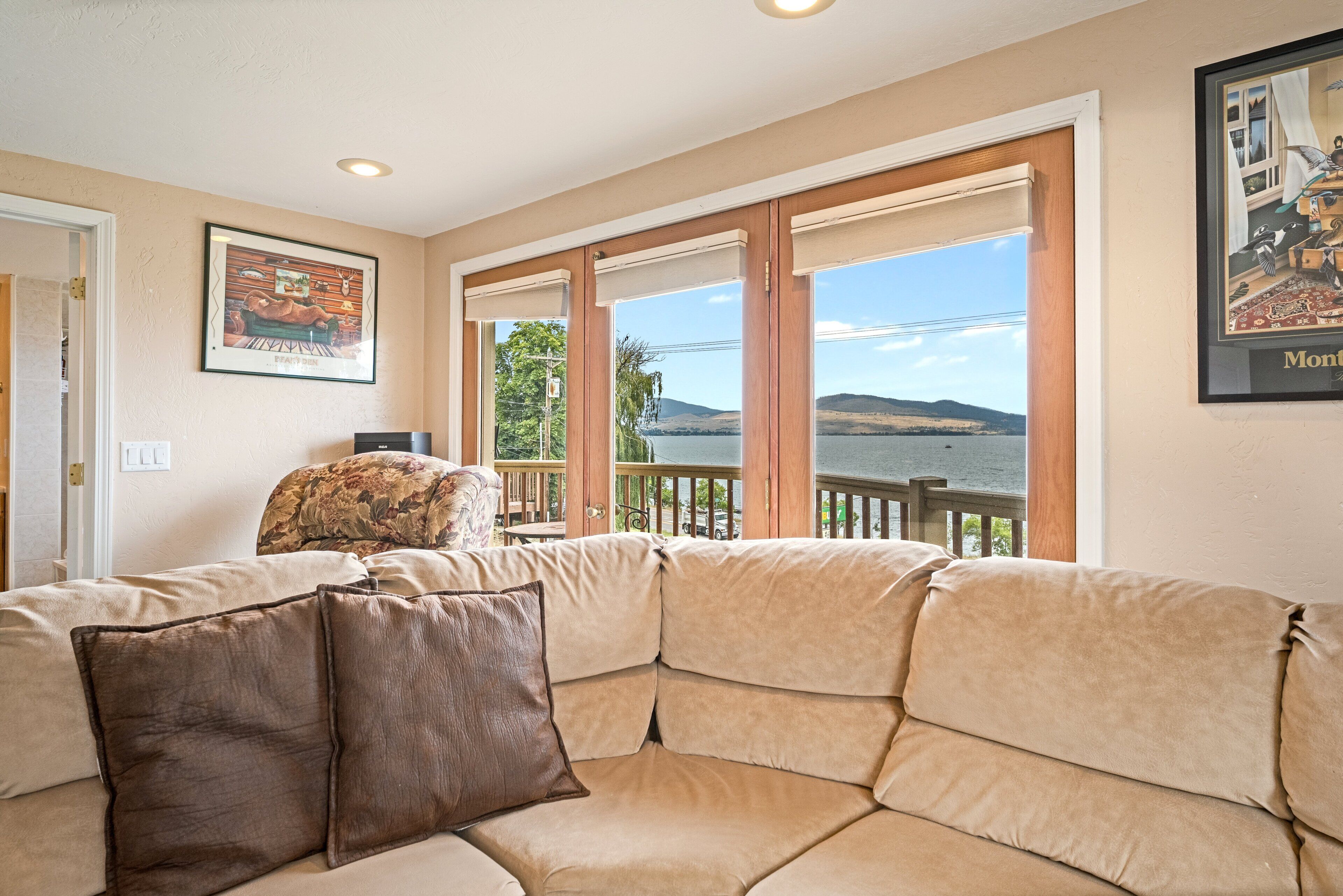A living room with a large window, a sofa, and a framed picture on the wall.