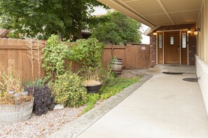 A covered outdoor area with a wooden fence, potted plants, and a barrel.
