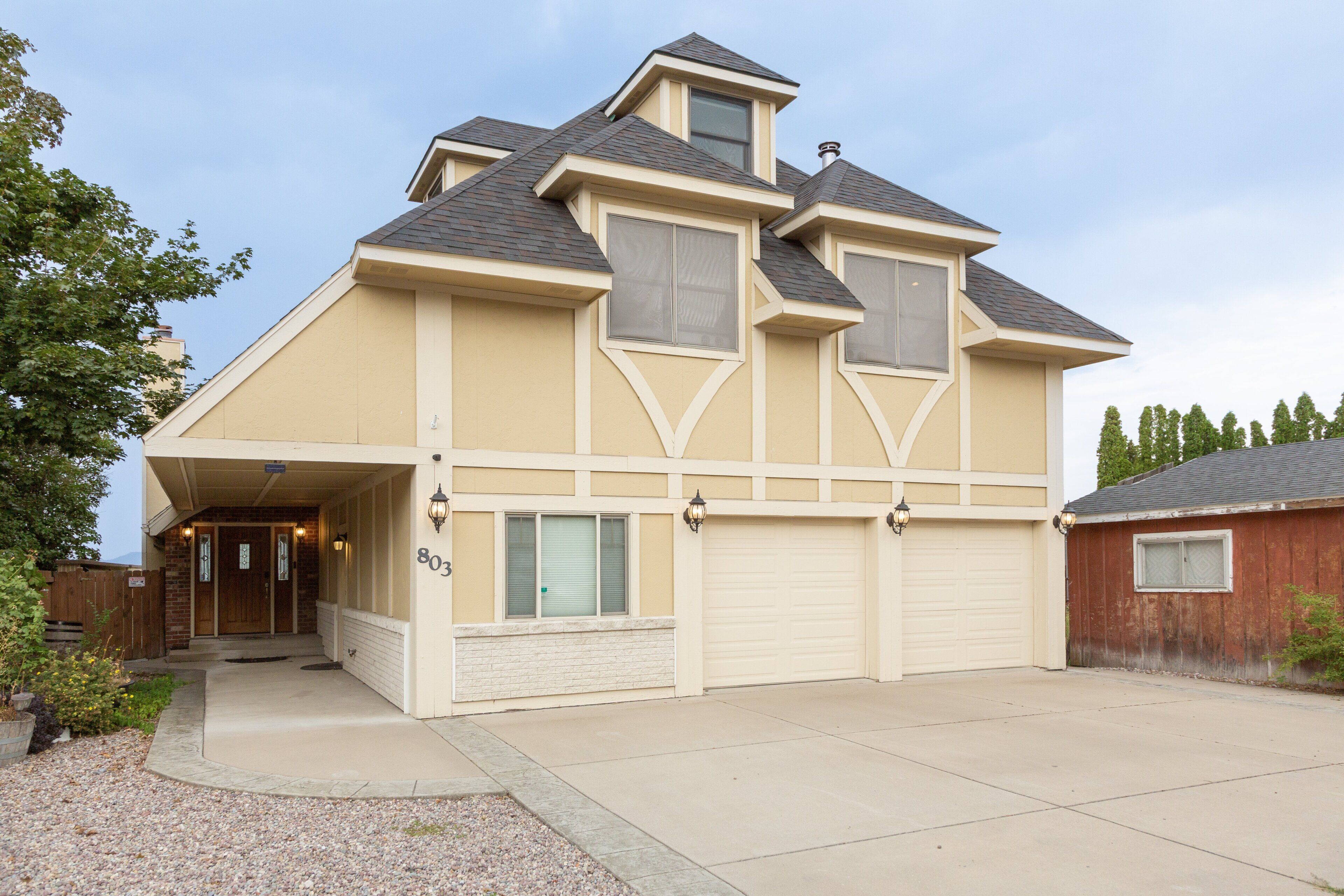 A two-story house with a garage, a covered porch, and a small attached shed.