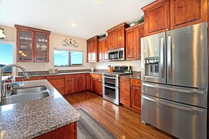 A kitchen with wooden cabinets, stainless steel appliances, granite countertops, and a window.