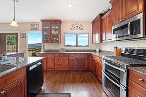 A kitchen with wooden cabinets, a built-in oven, a microwave, and a dishwasher.