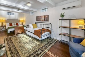 Une chambre d’hôtel avec un lit, des tables de chevet, une bibliothèque et une grande fenêtre.
