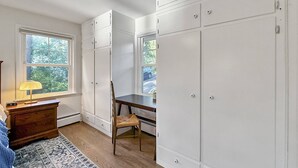 Una habitación con escritorio, silla, armario y ventana con vistas al exterior.