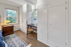 Une pièce comprenant un bureau, une chaise, une armoire et une fenêtre donnant sur l’extérieur.