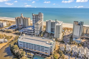 A coastal hotel complex with multiple high-rise buildings, a parking structure, and a beach view. - Dunes Village Oceanfront Condo + Waterpark (Myrtle Beach)