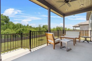 A covered outdoor patio with a table and chairs, a ceiling fan, and a view of a green landscape. - Fully furnished and appointed home for corporate lease.   All utilities paid. (Manor)
