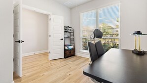 Ein Zimmer mit Esstisch, Stühlen, Deckenventilator und einem Fenster mit Jalousien.