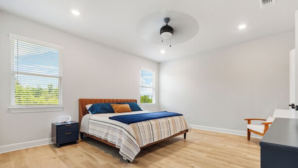 Ein Schlafzimmer mit Bett, Nachttischen, Deckenventilator und Fenster.