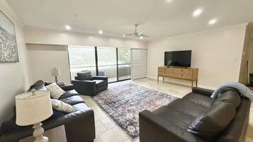 A modern living room with a sofa, a television, and a large window.