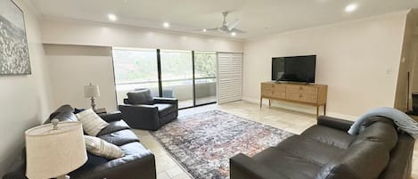 A modern living room with a sofa, a television, and a large window.