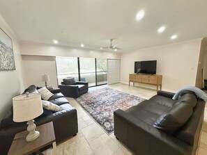 A modern living room with a sofa, a television, and a large window.