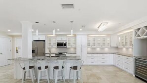 A modern kitchen with white cabinetry, a central island with bar stools, stainless steel appliances, and pendant lighting. - 3 bedroom condo fully updated- Innisbrook Resort (Palm Harbor)