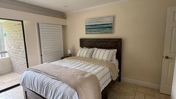 A bedroom with a bed, a nightstand, a painting, and a door.