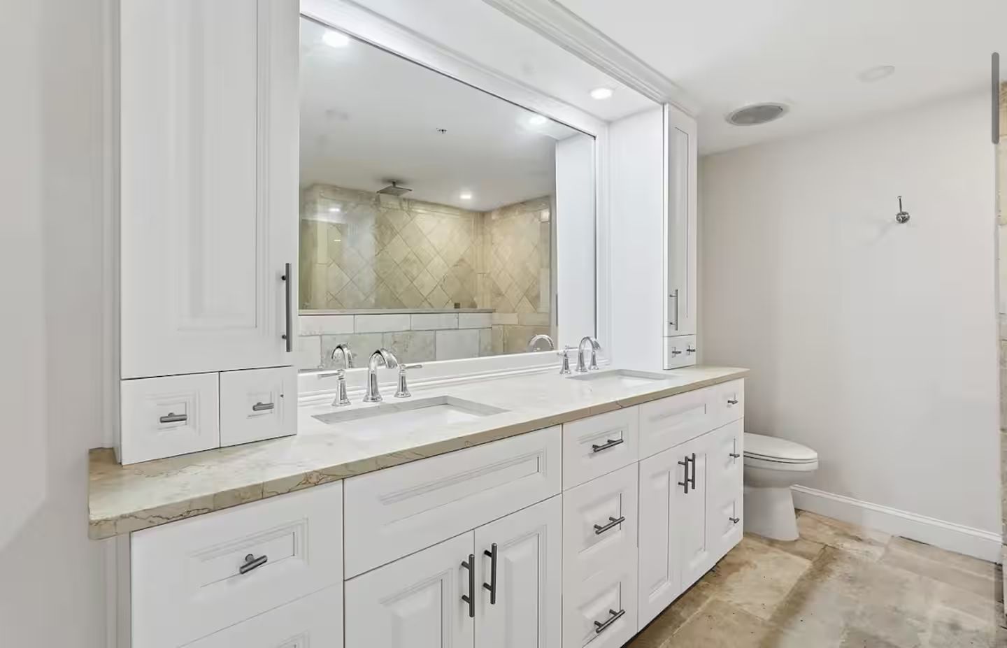 A modern bathroom with a double sink vanity, a large mirror, and a toilet.