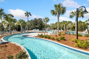 A swimming pool with a curved design, surrounded by lounge chairs and palm trees. - Steps to Beach, Prime WaterColor Location! 2 Bikes Included! (Santa Rosa Beach)