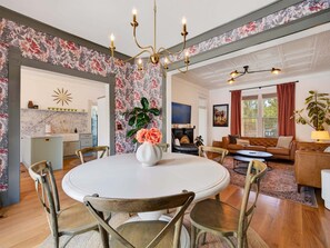 A dining area with a round table, chairs, a vase with flowers, and a chandelier. - Historic Manor w/ Hidden Speakeasy, 3BR/2.5BA (Heber City)